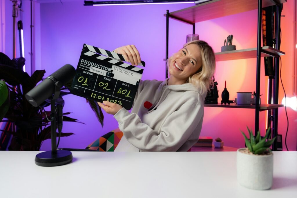 Creator holding a clapperboard at a desk with a microphone